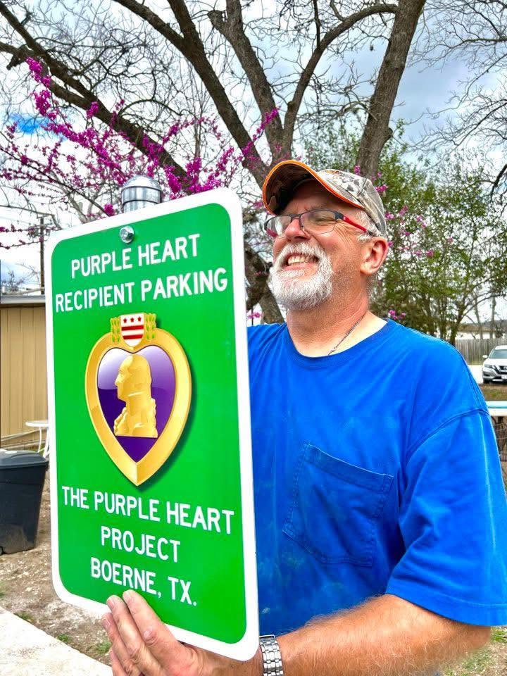 Volunteer holding a Purple Heart Recipient Parking sign